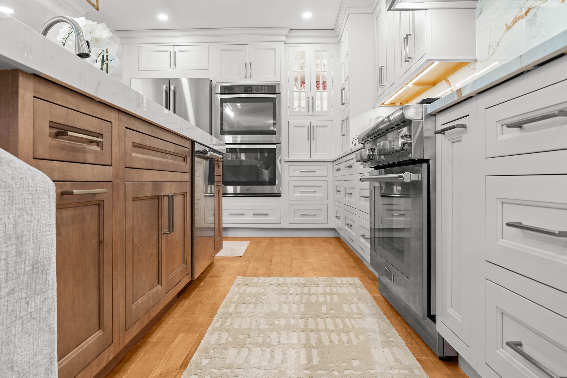Bright modern kitchen with white cabinets, wood island, stainless appliances, and a runner rug.