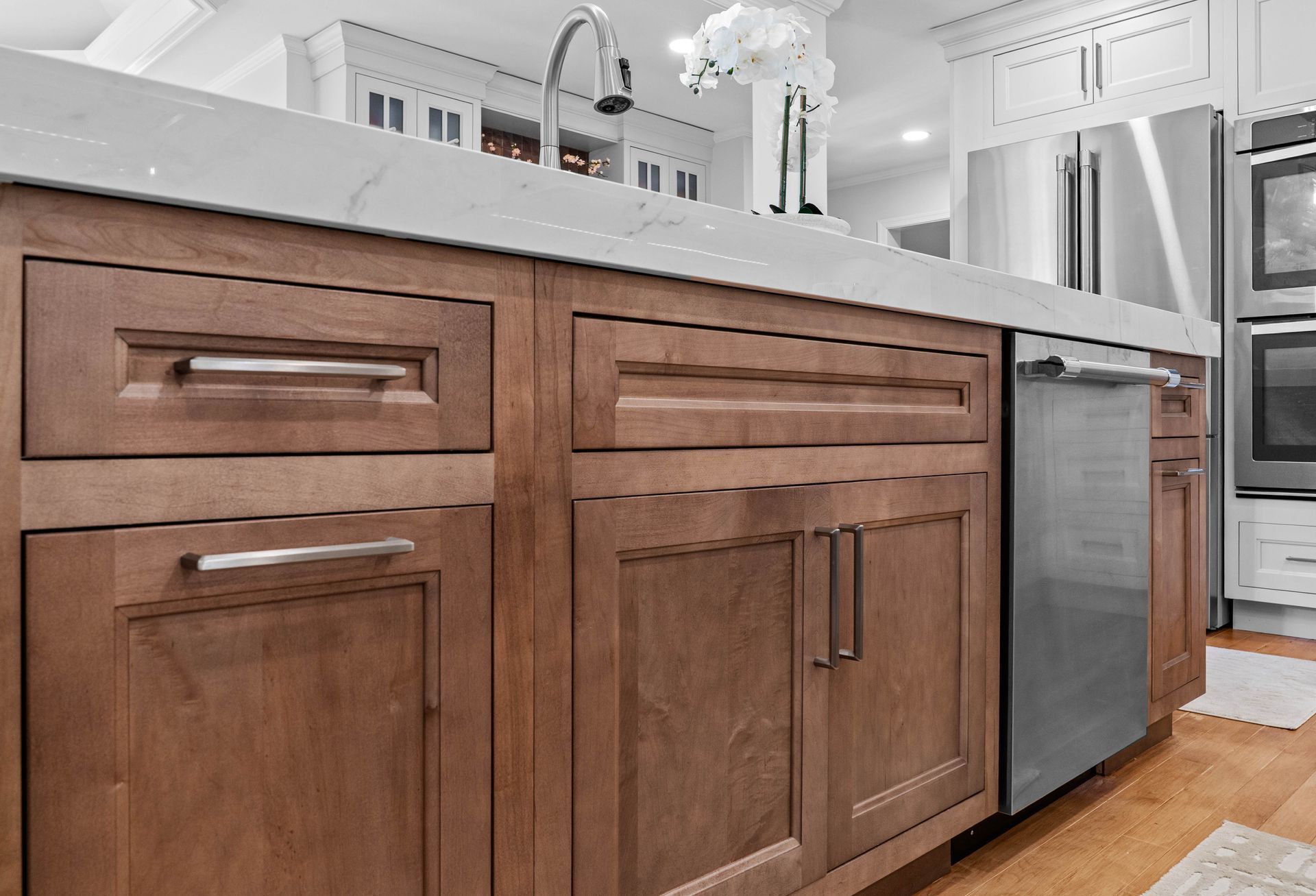 Wooden kitchen cabinets with stainless steel dishwasher and white countertop in a modern kitchen