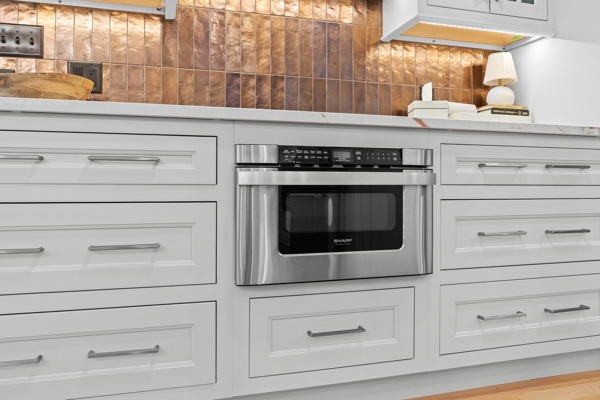Built-in stainless steel microwave in white kitchen cabinets with wood backsplash