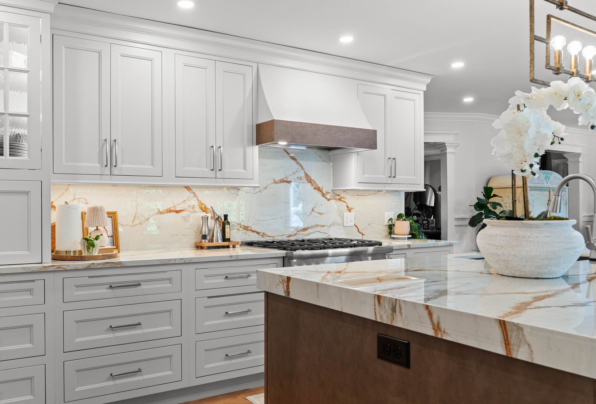 Bright white luxury kitchen with marble island, built-in cabinets, and gold accents