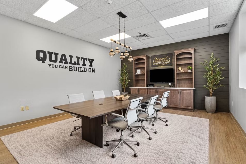 Modern conference room with wood table, white chairs, built-in cabinets, and “QUALITY” wall sign
