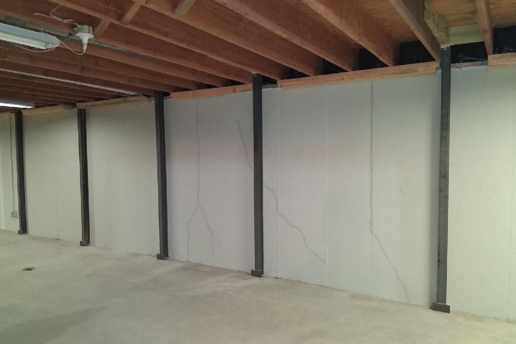 Concrete pathway next to a white cinder block wall with a dark base, in an outdoor setting.