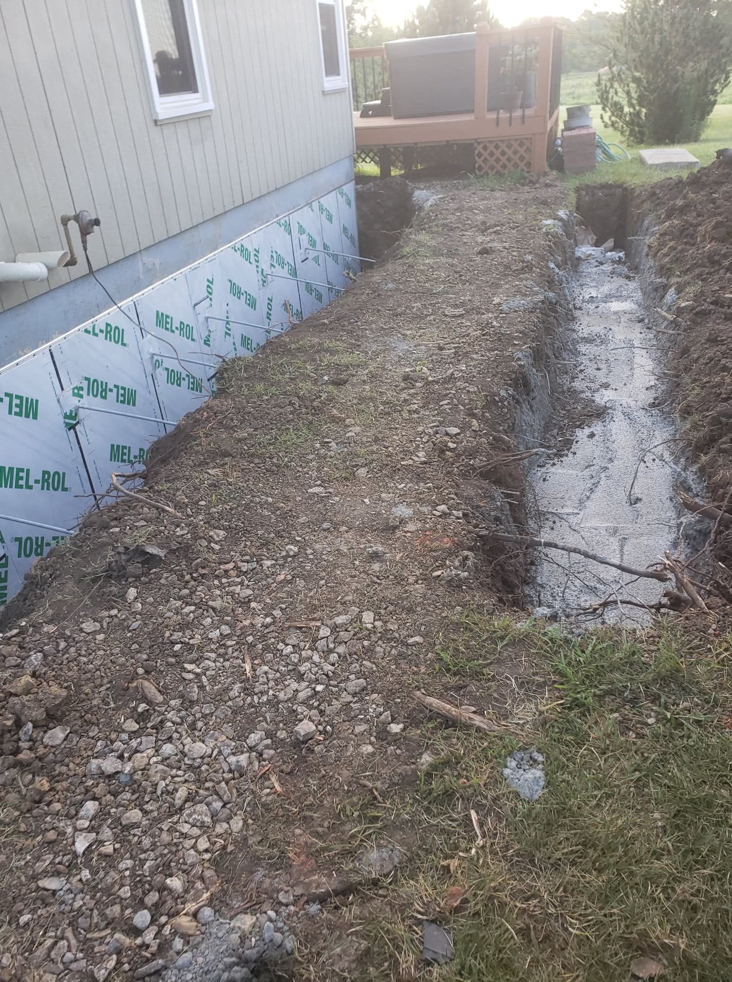 Sump pump system with pipes in a concrete basement. Includes a yellow pump, dark basin, and standing water.