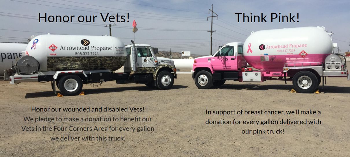 Two pink trucks are parked next to each other in a dirt field.