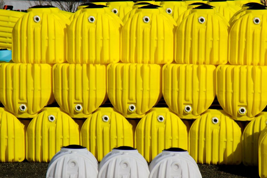 Bright yellow, cylindrical containers stacked in rows. Two white containers at the bottom.