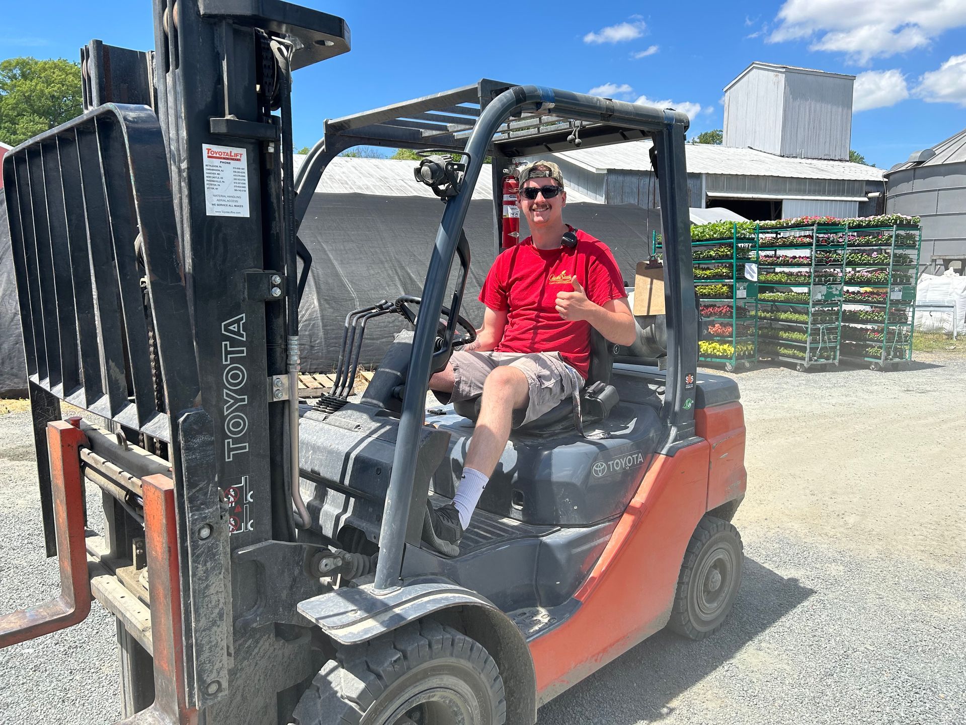 A man in a red shirt is sitting in a forklift