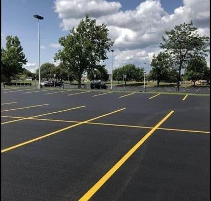 A parking lot with yellow lines and trees in the background