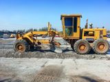 A yellow tractor is sitting on top of a dirt field