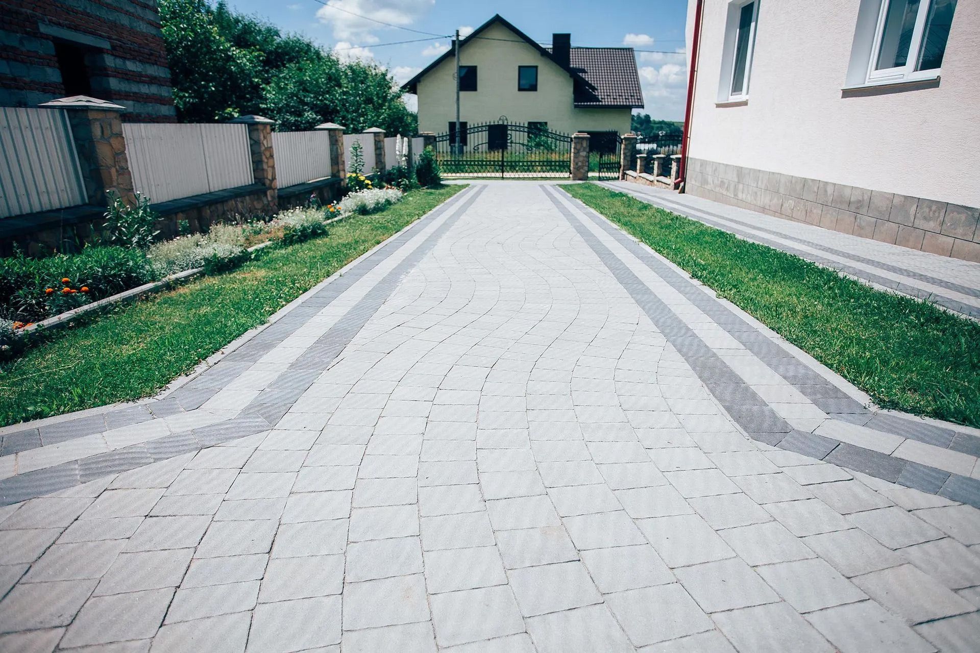 A brick driveway with a house in the background