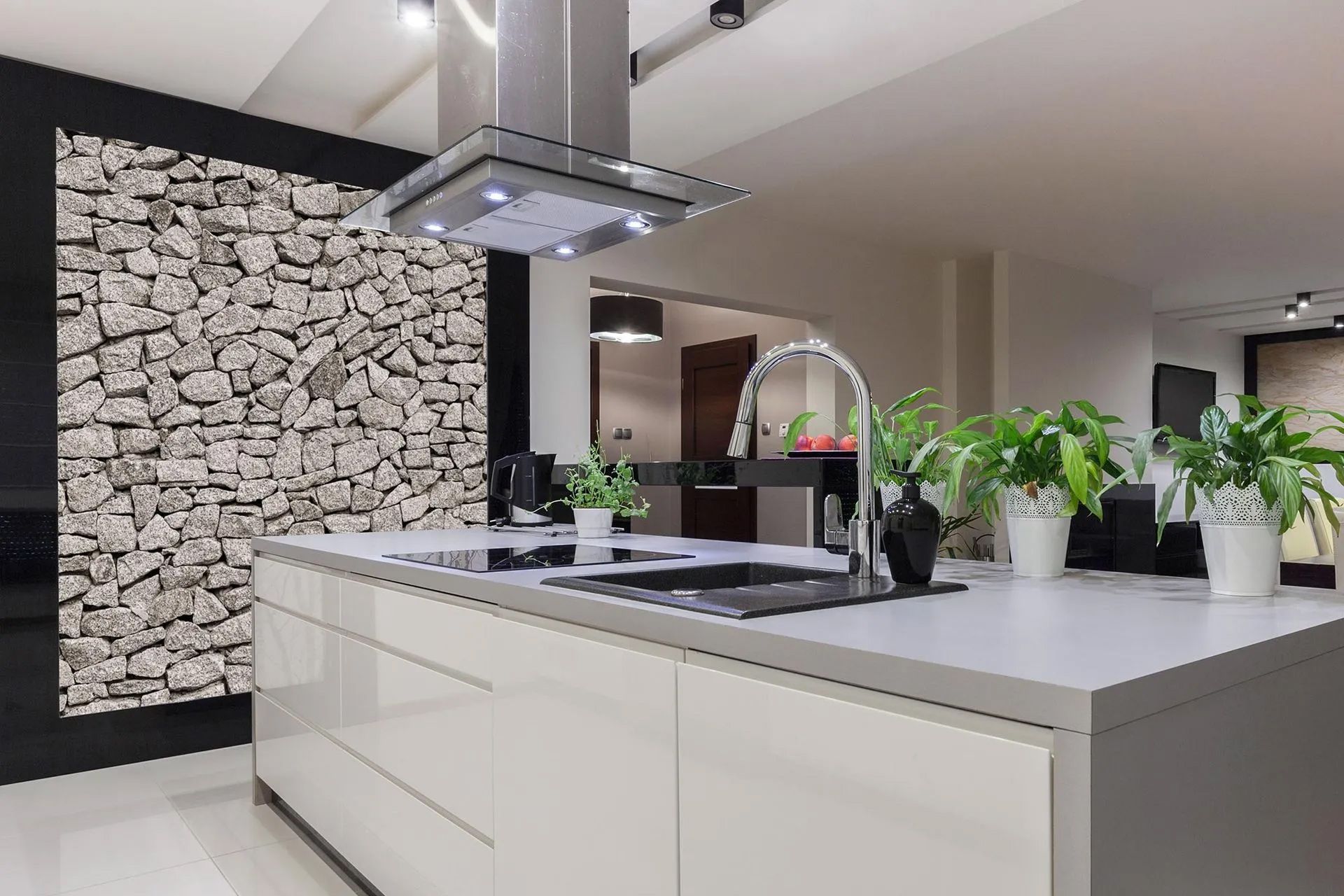 A kitchen with white cabinets and a stone wall
