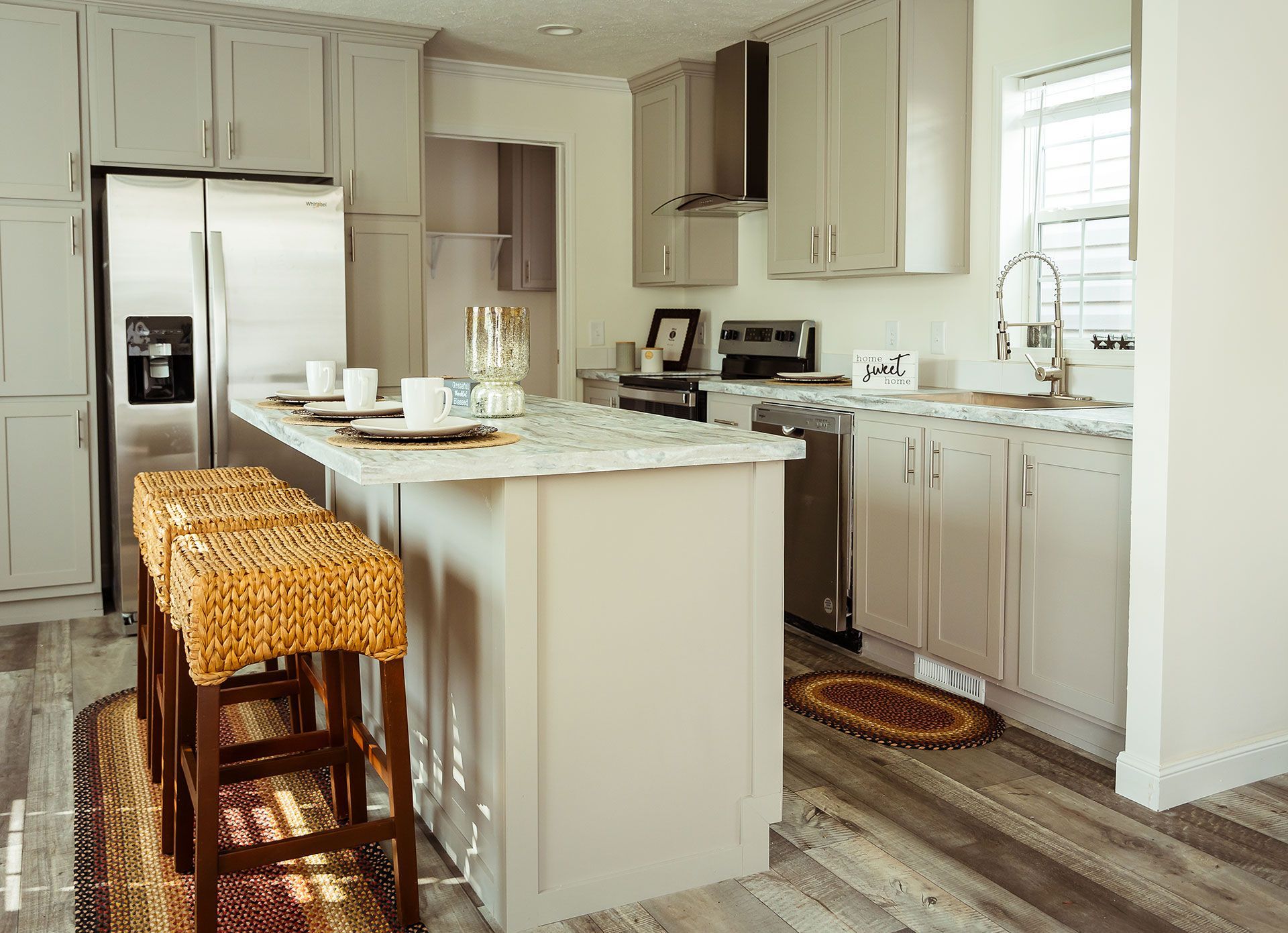 A kitchen with white cabinets, stainless steel appliances, and a large island