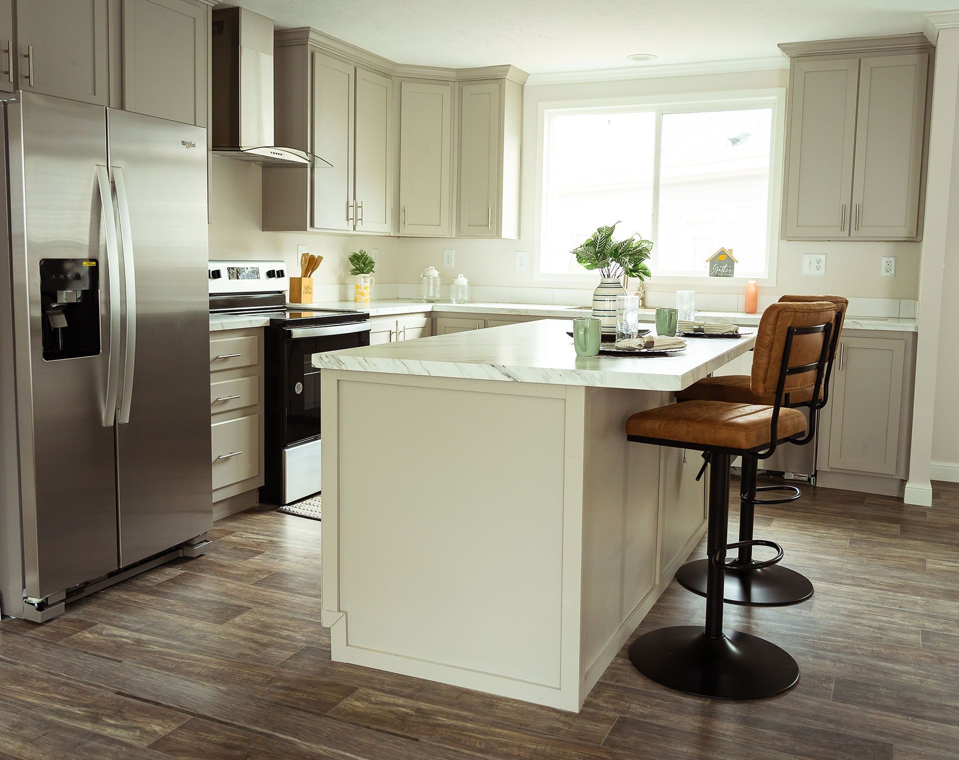 A kitchen with stainless steel appliances, white cabinets, and a large island