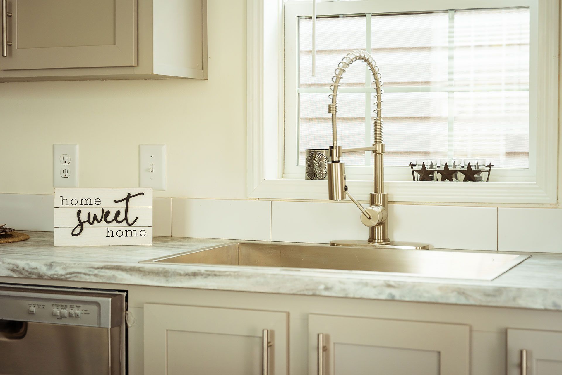 A kitchen sink with a sign on the counter that says home sweet home