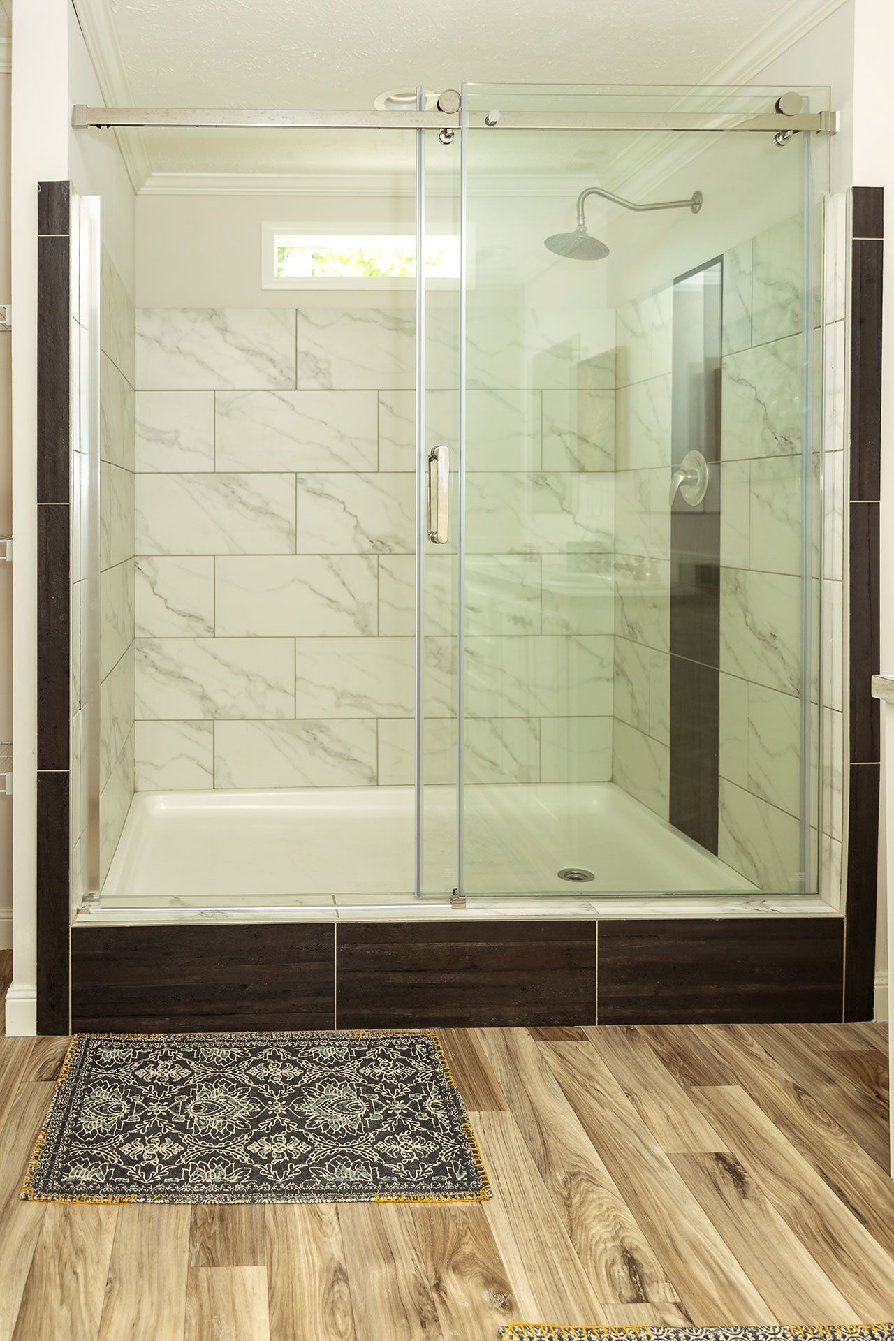 A bathroom with a walk in shower and a rug on the floor