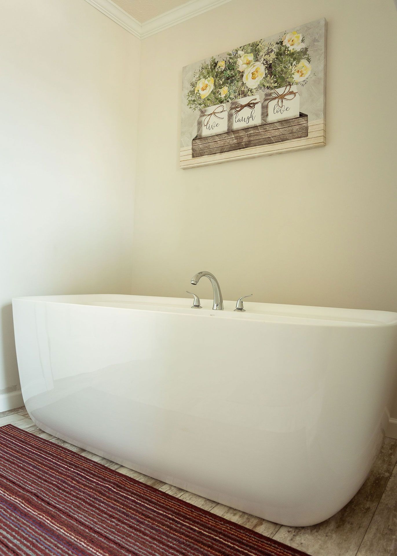 A bathtub in a bathroom with a painting on the wall above it