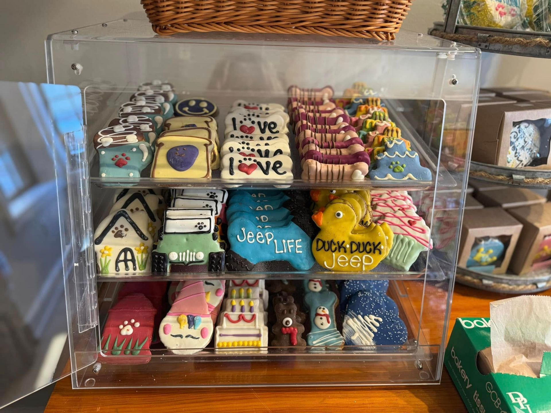 Display case with colorful decorated cookies, including houses, hearts, and animals, on shelves.