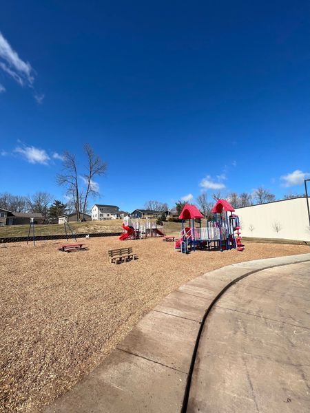 Playground with colorful equipment, wood chip ground cover, and blue sky.