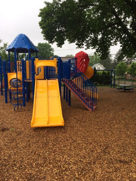 Playground with blue, yellow, and red structures on wood chips.