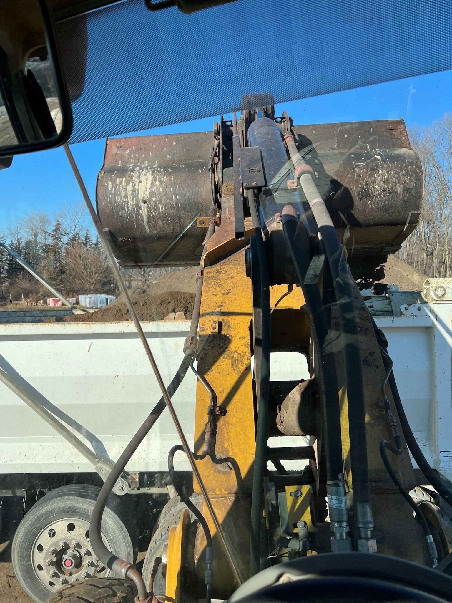 Excavator loading a dump truck with dirt on a sunny day.