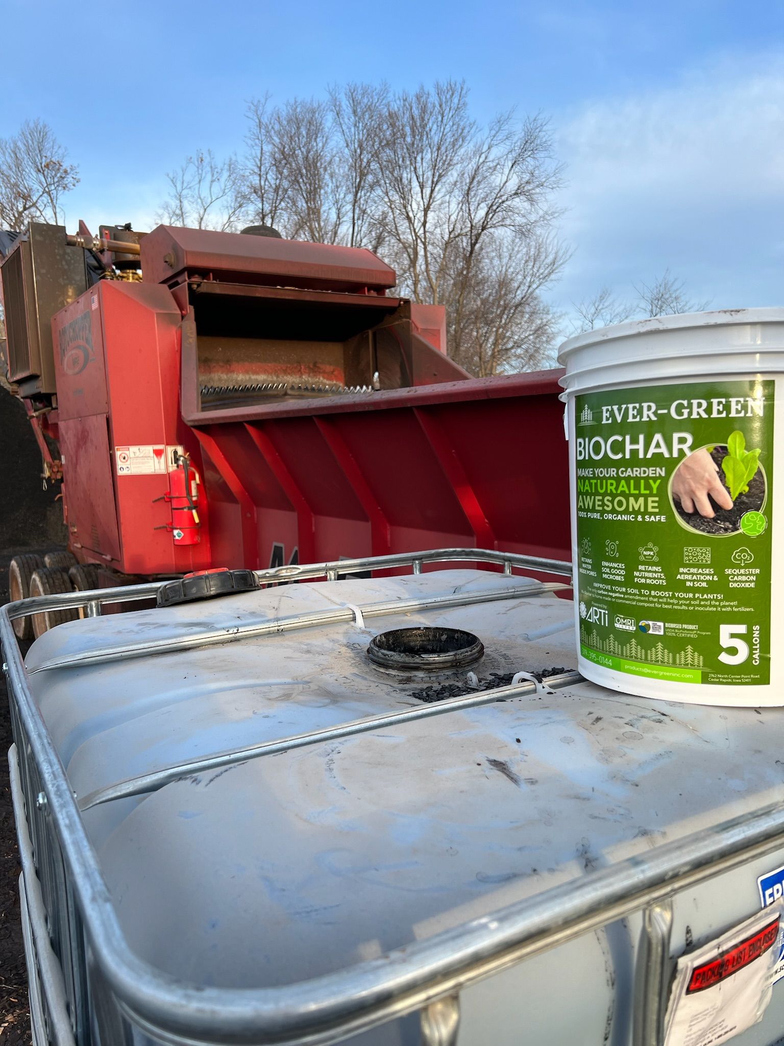 A red industrial machine and a green bucket labeled 