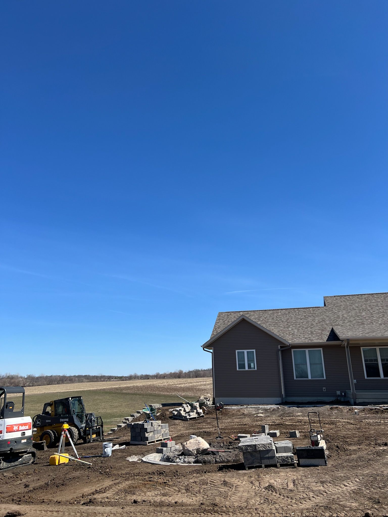 Construction site with a house, equipment, and materials under a blue sky.