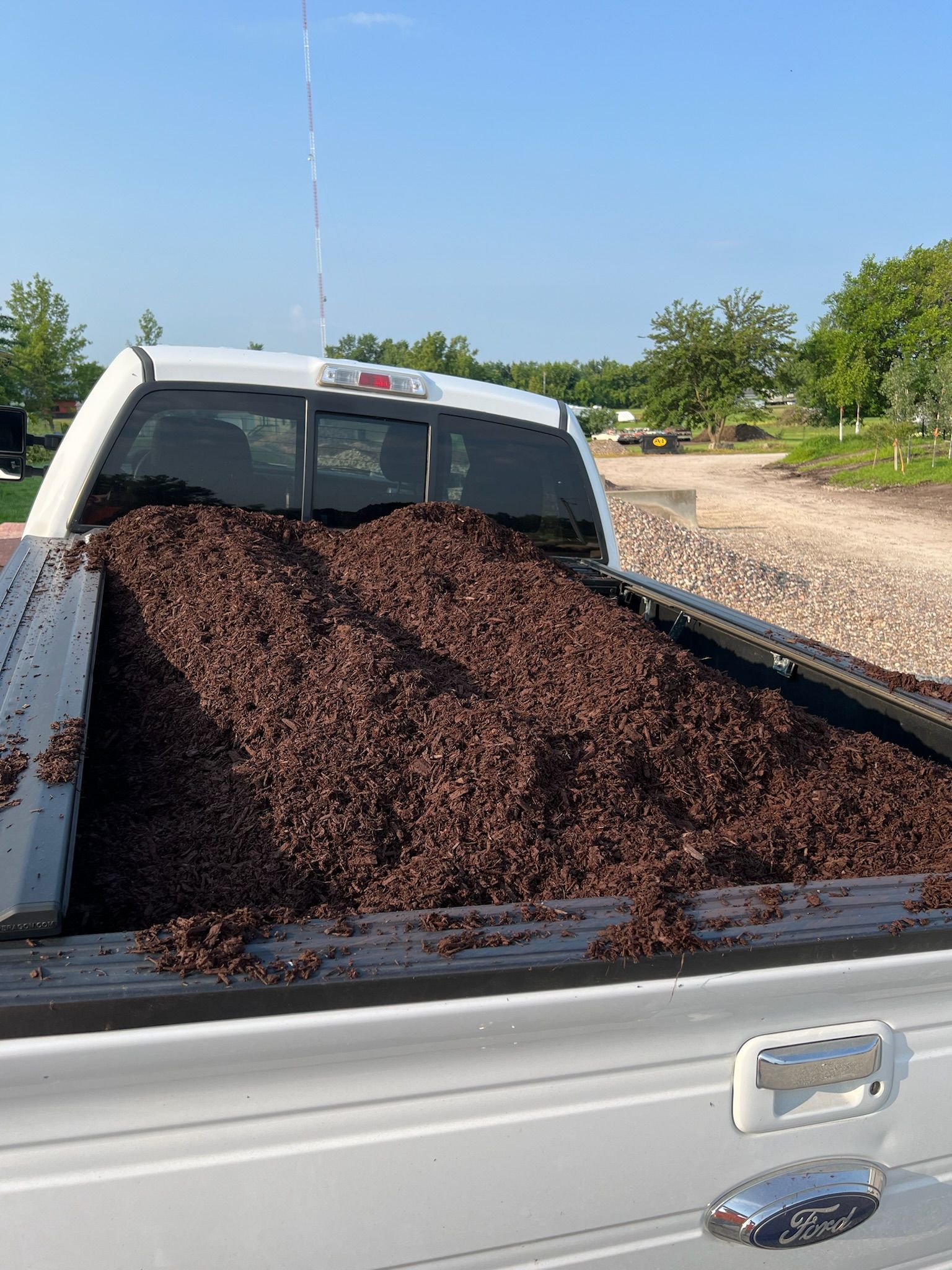 Pickup truck bed overflowing with dark brown mulch.
