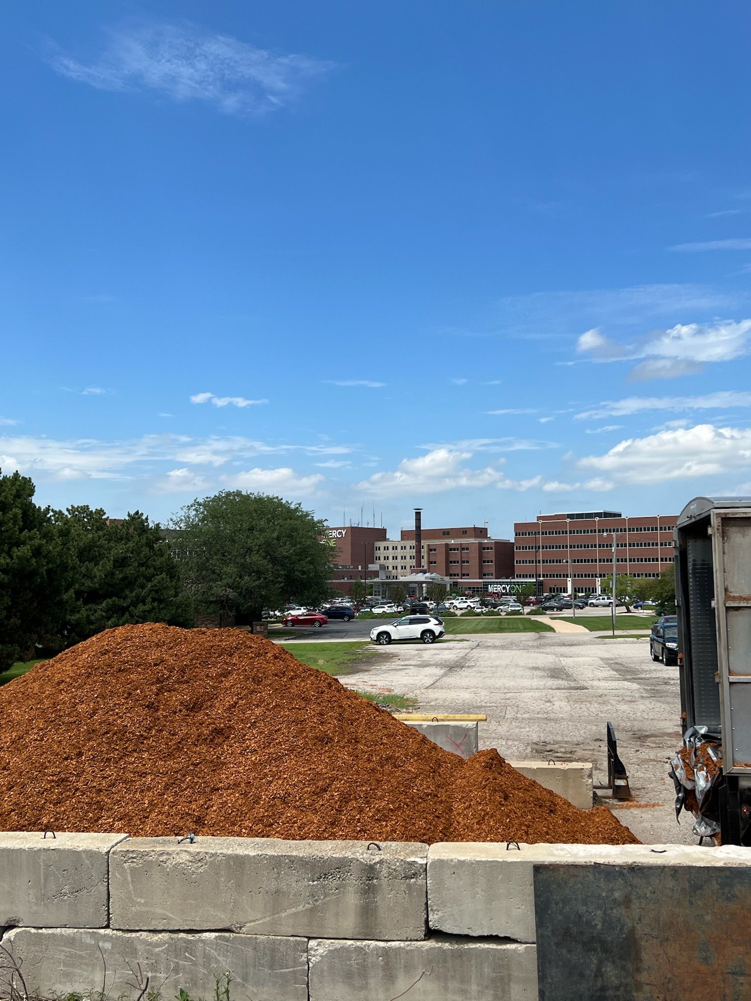 Pile of wood chips in front of a hospital on a sunny day. Blue sky.