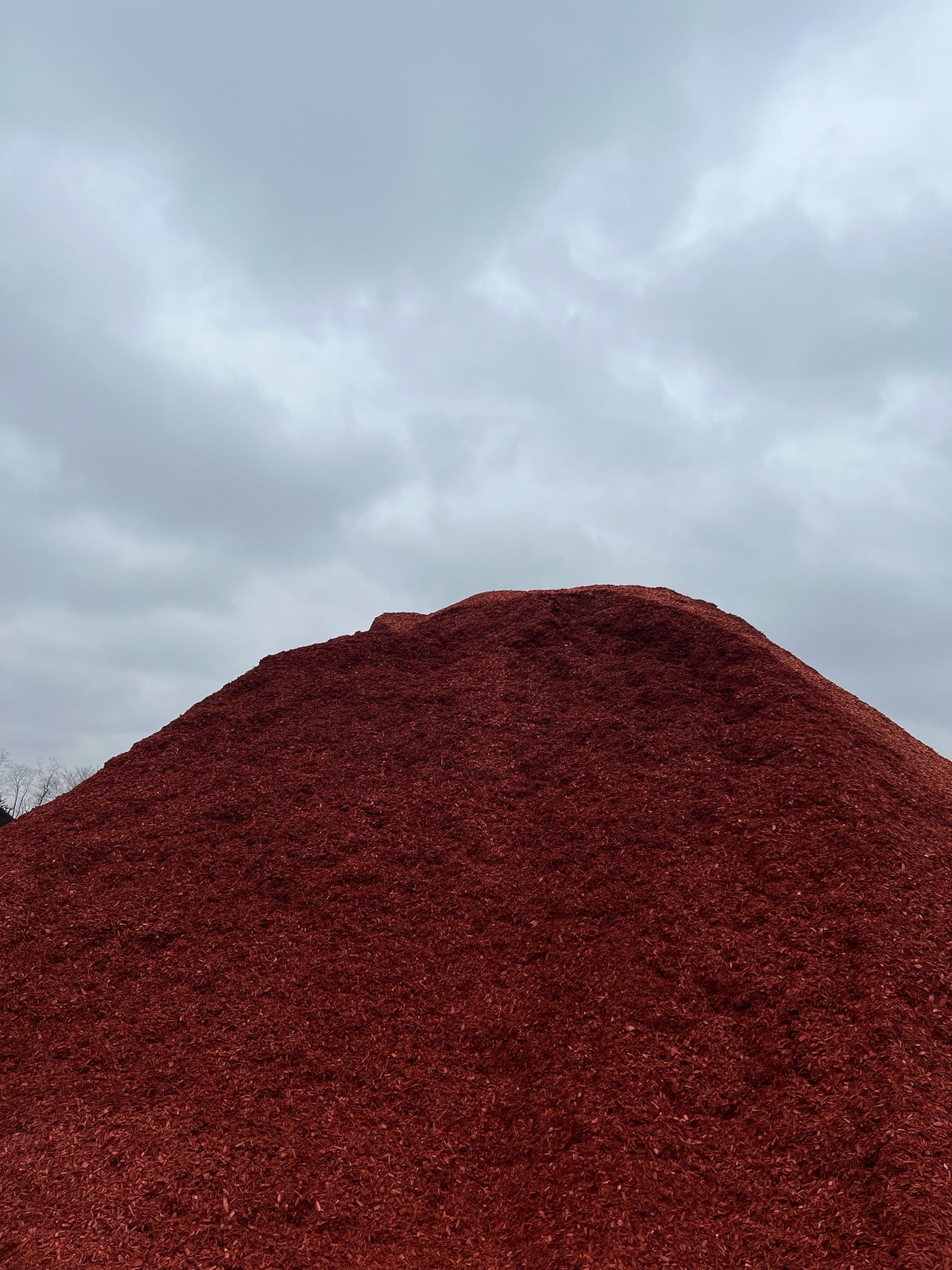 Pile of reddish-brown material under a cloudy gray sky.