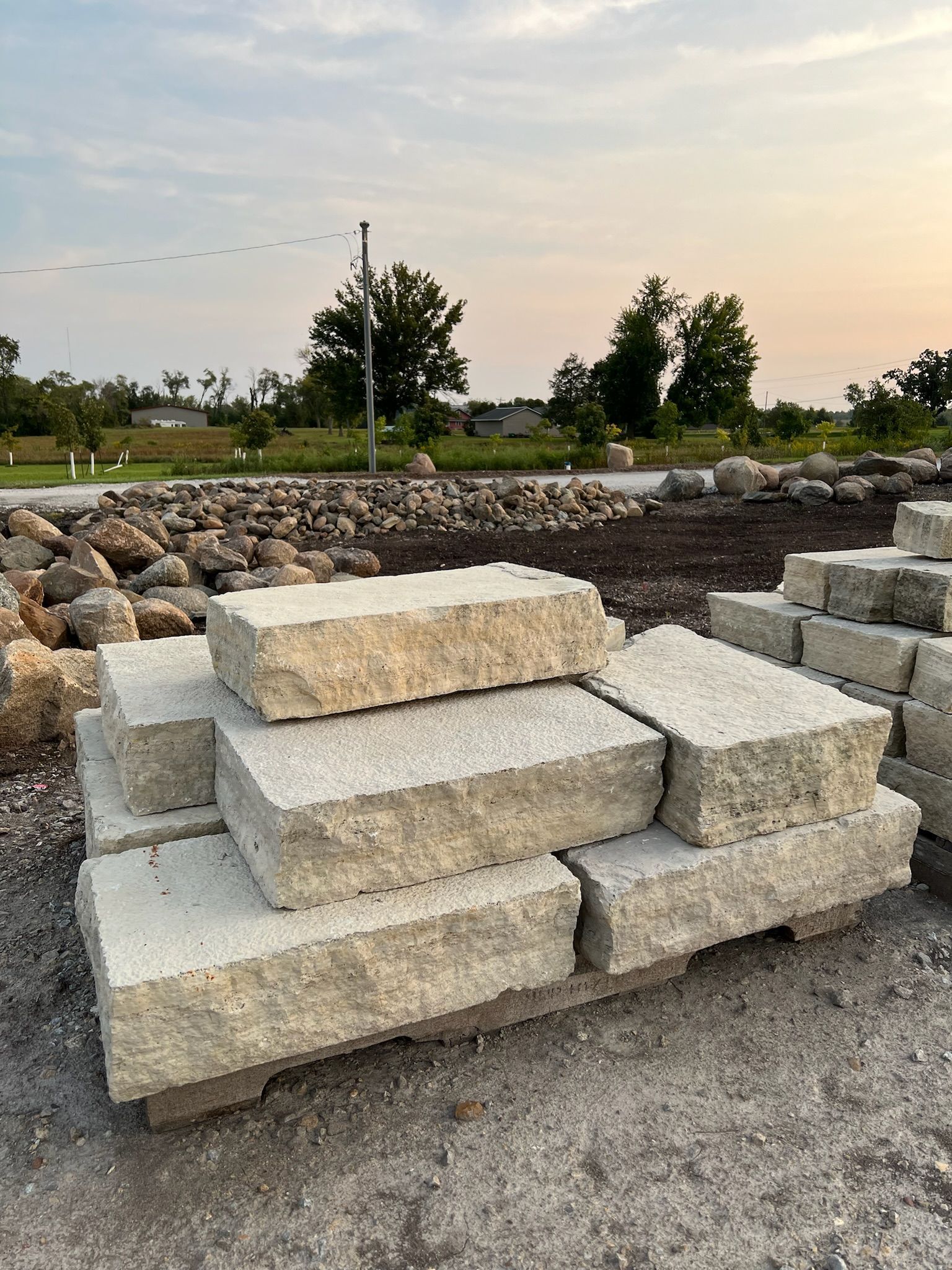 Pile of various-colored landscaping rocks on dark mulch.