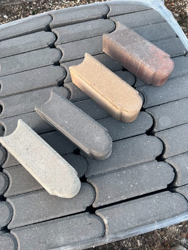 Four colorful pavers on top of a stack of gray pavers.