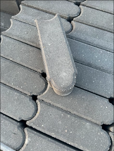Stack of gray interlocking paving stones, one upright.