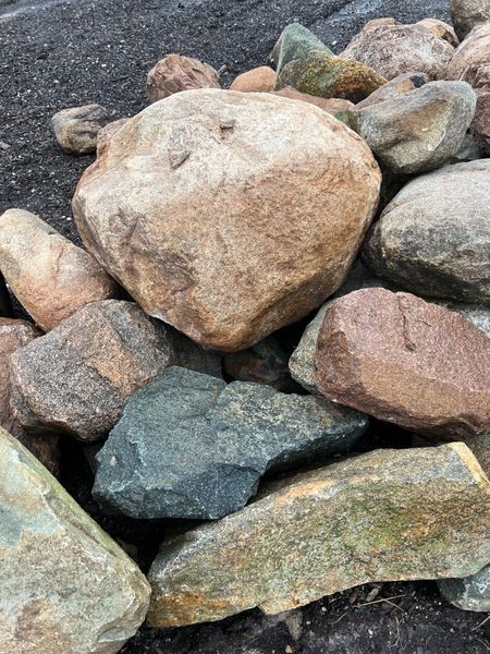Pile of varied rocks with tan, brown, blue, and green hues.