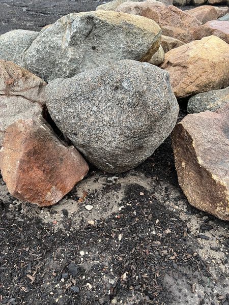 Pile of multicolored, irregularly shaped rocks on dark dirt.
