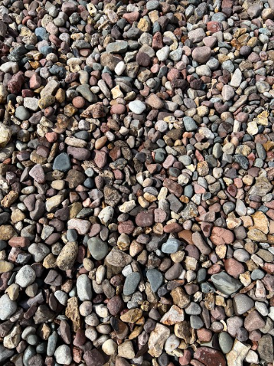 Close-up of a pile of small, rounded pebbles in shades of brown, gray, and red.