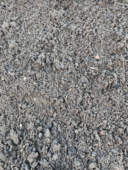 Close-up of dark, rich soil with various textures, small rocks, and organic matter.
