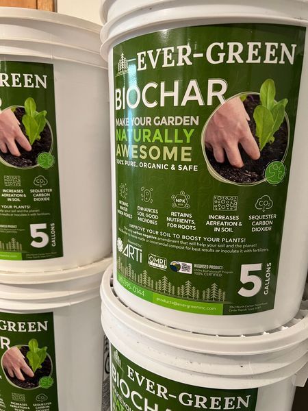 Buckets of Ever-Green Biochar. White buckets with green labels showing hands planting a seedling.