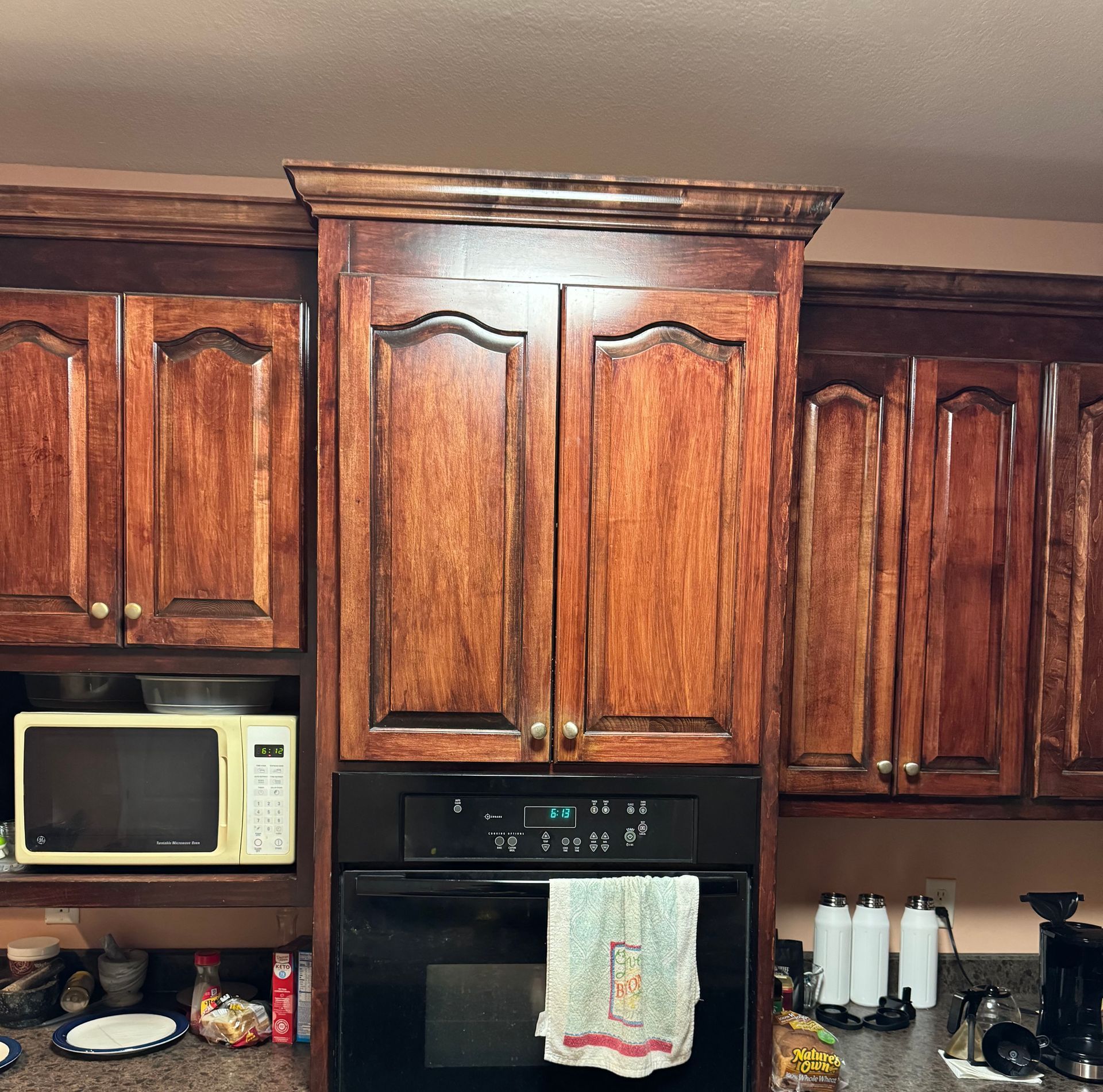 Kitchen cabinets with a built-in oven and microwave. The cabinets have a dark wood stain.