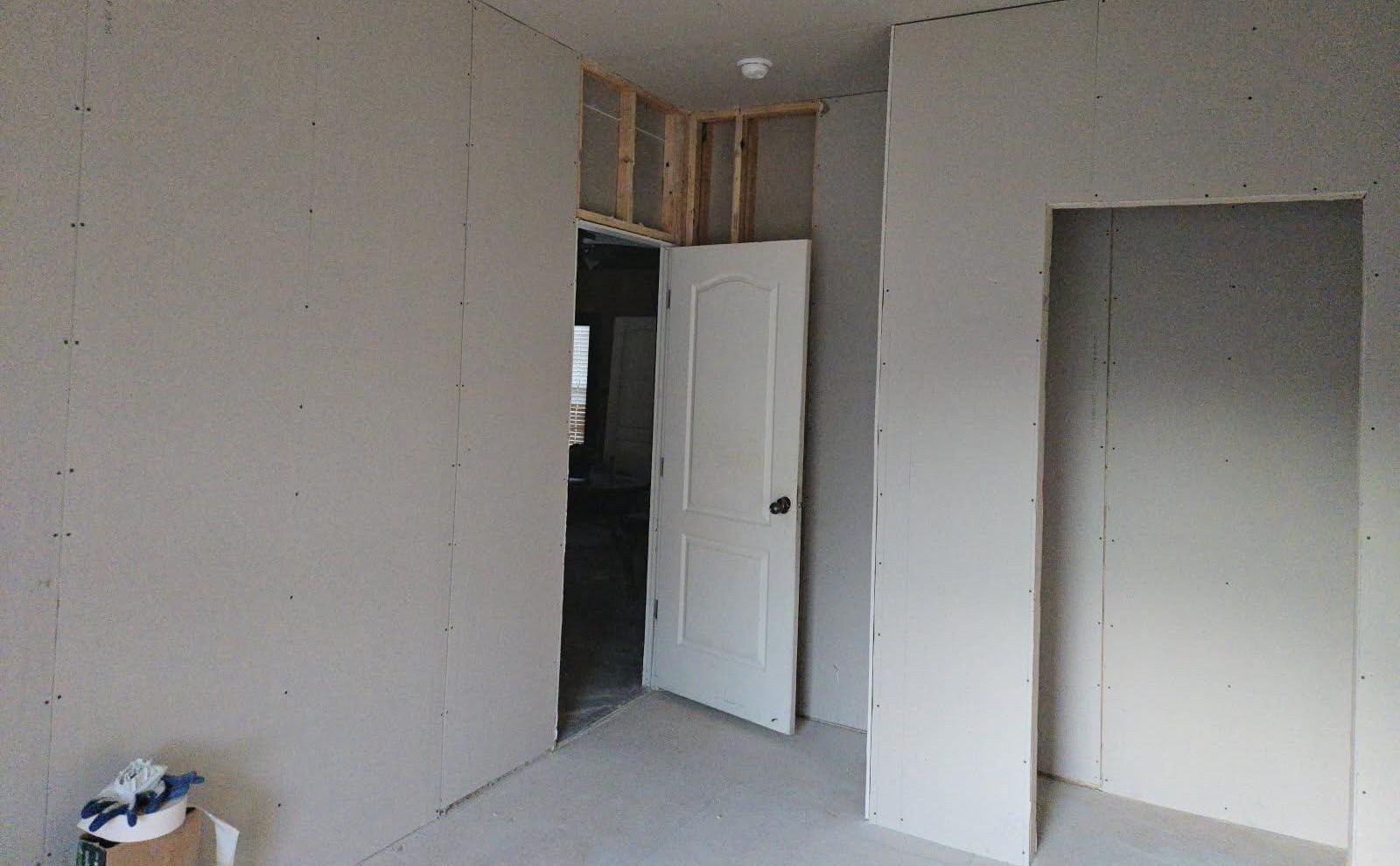 Room with unfinished walls, doorway, and a partially framed area above a door.