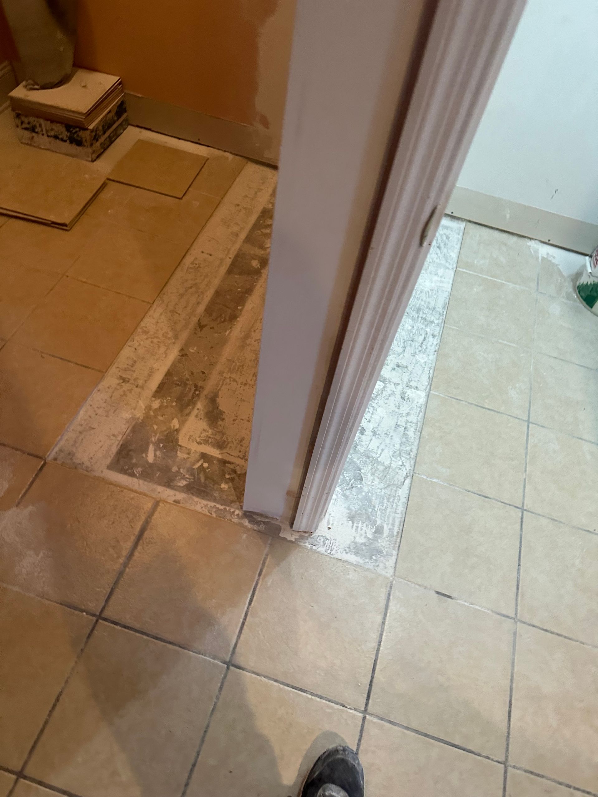 Doorway with existing tile flooring and partially removed flooring underneath.