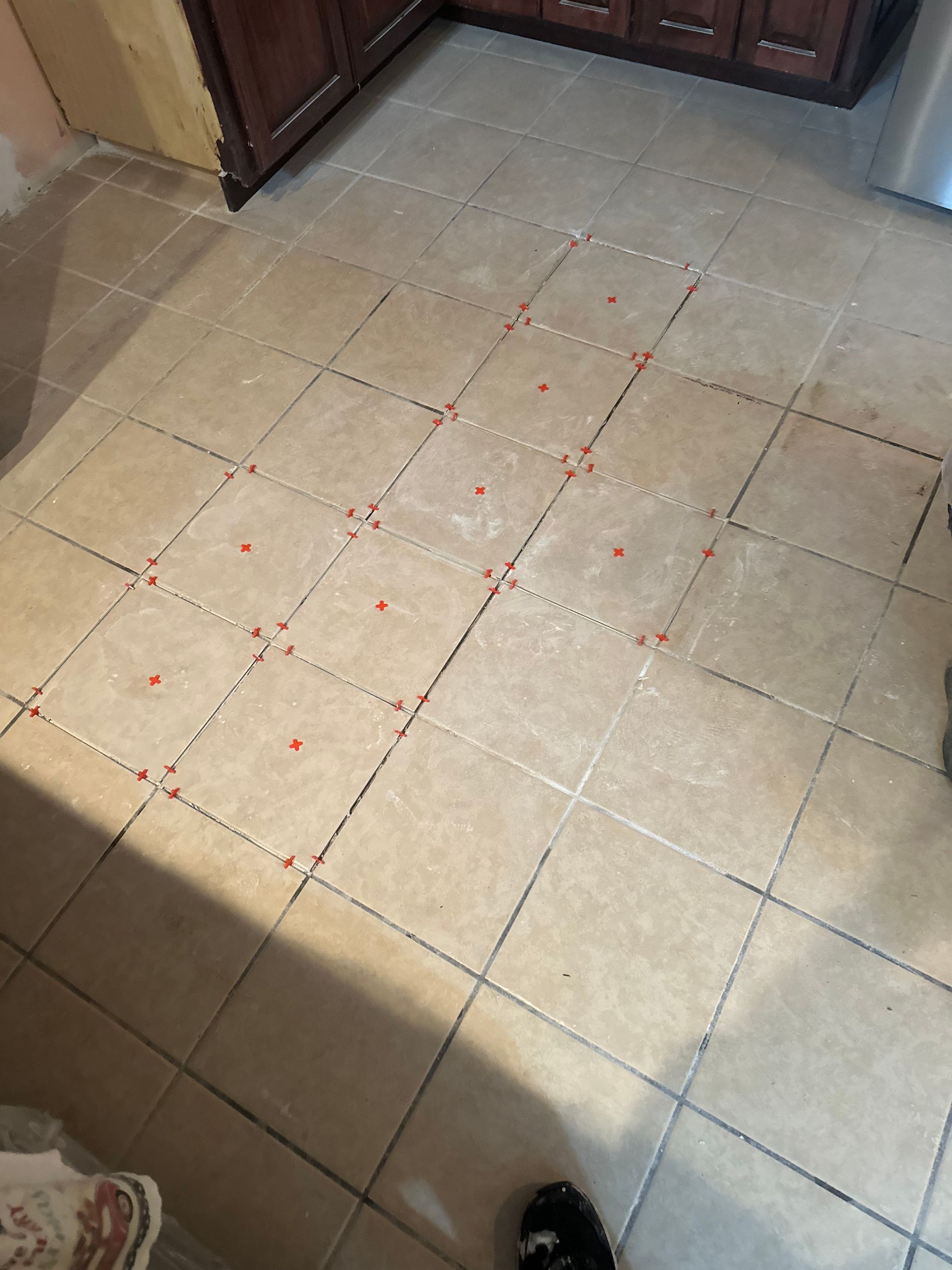 Floor tiles with red tile spacers set in a kitchen.