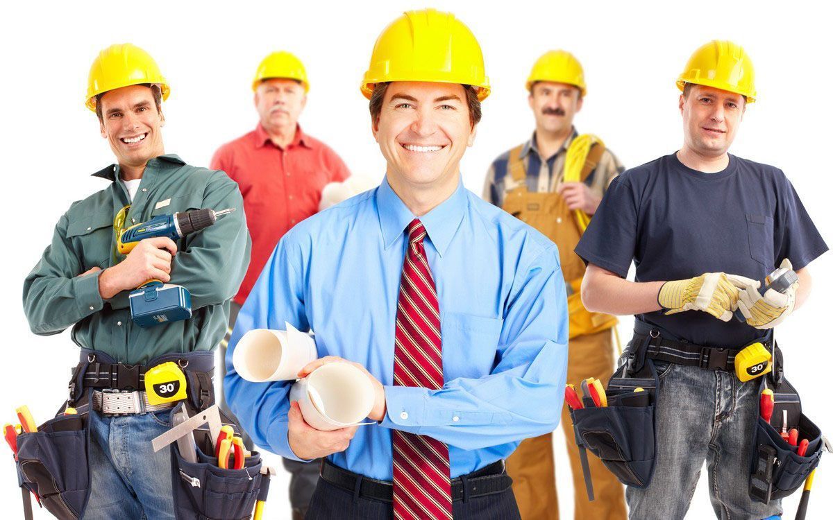 Smiling construction crew in hard hats holding tools, with one man in a blue shirt centered in front.