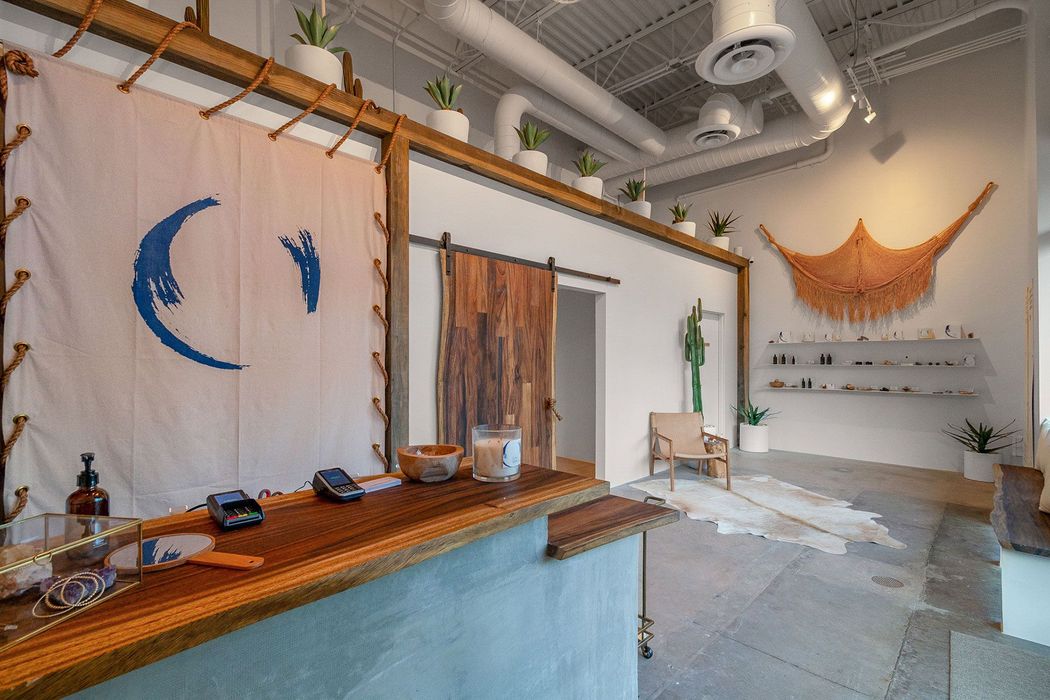 Modern airy room with wooden counter, wall art, hanging decor, and shelves in a minimalist interior