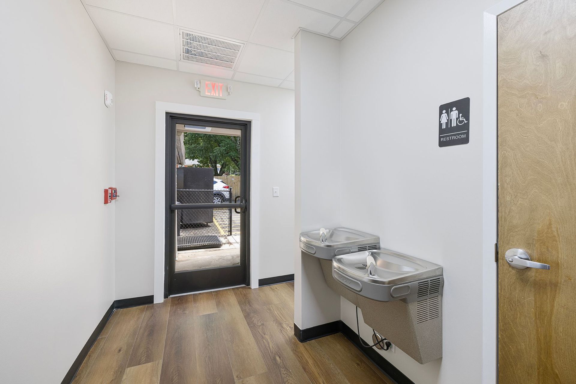 Hallway with drinking fountains and an open door to an outdoor area