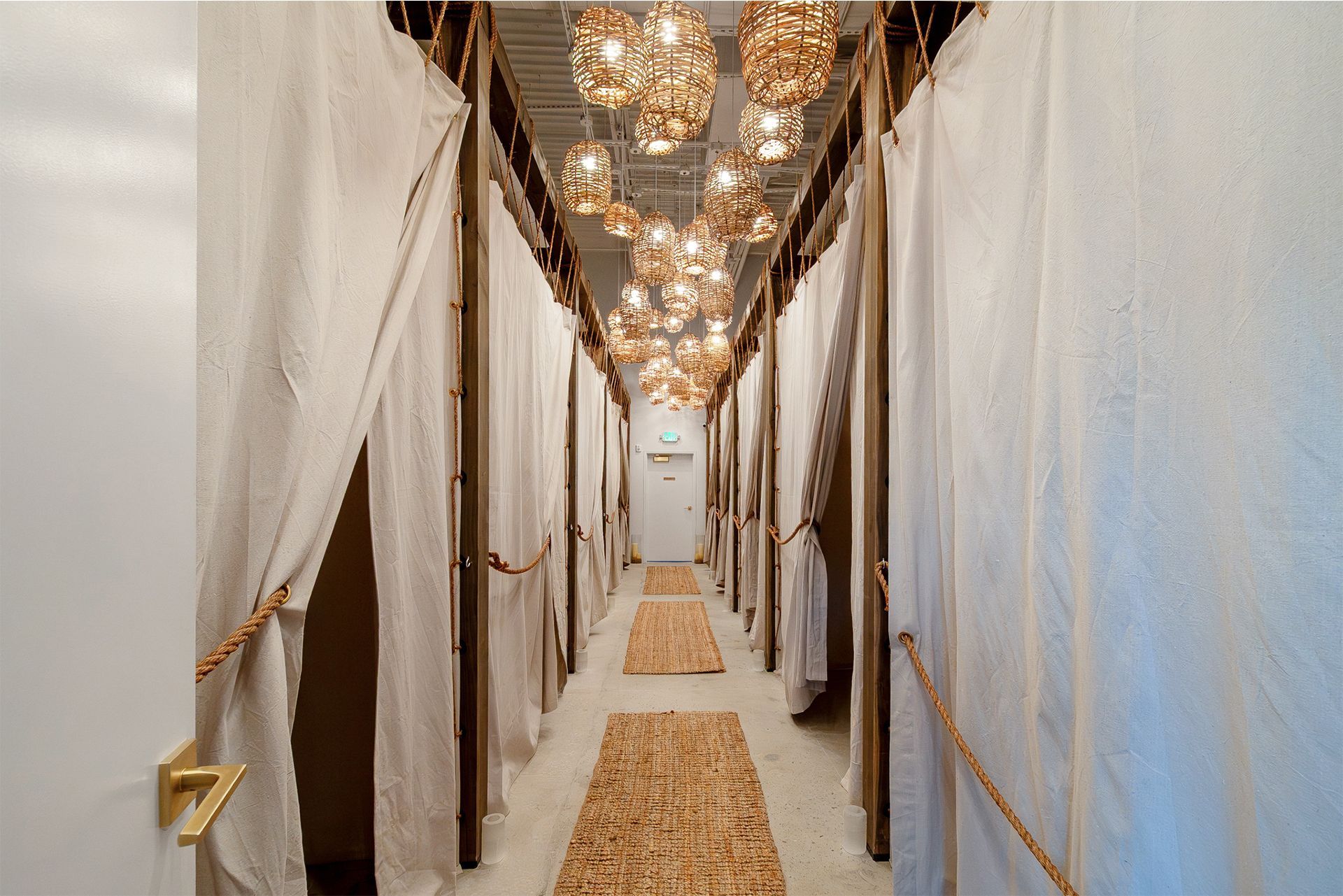 Elegant hallway with draped white curtains, warm hanging lights, and a woven runner carpet