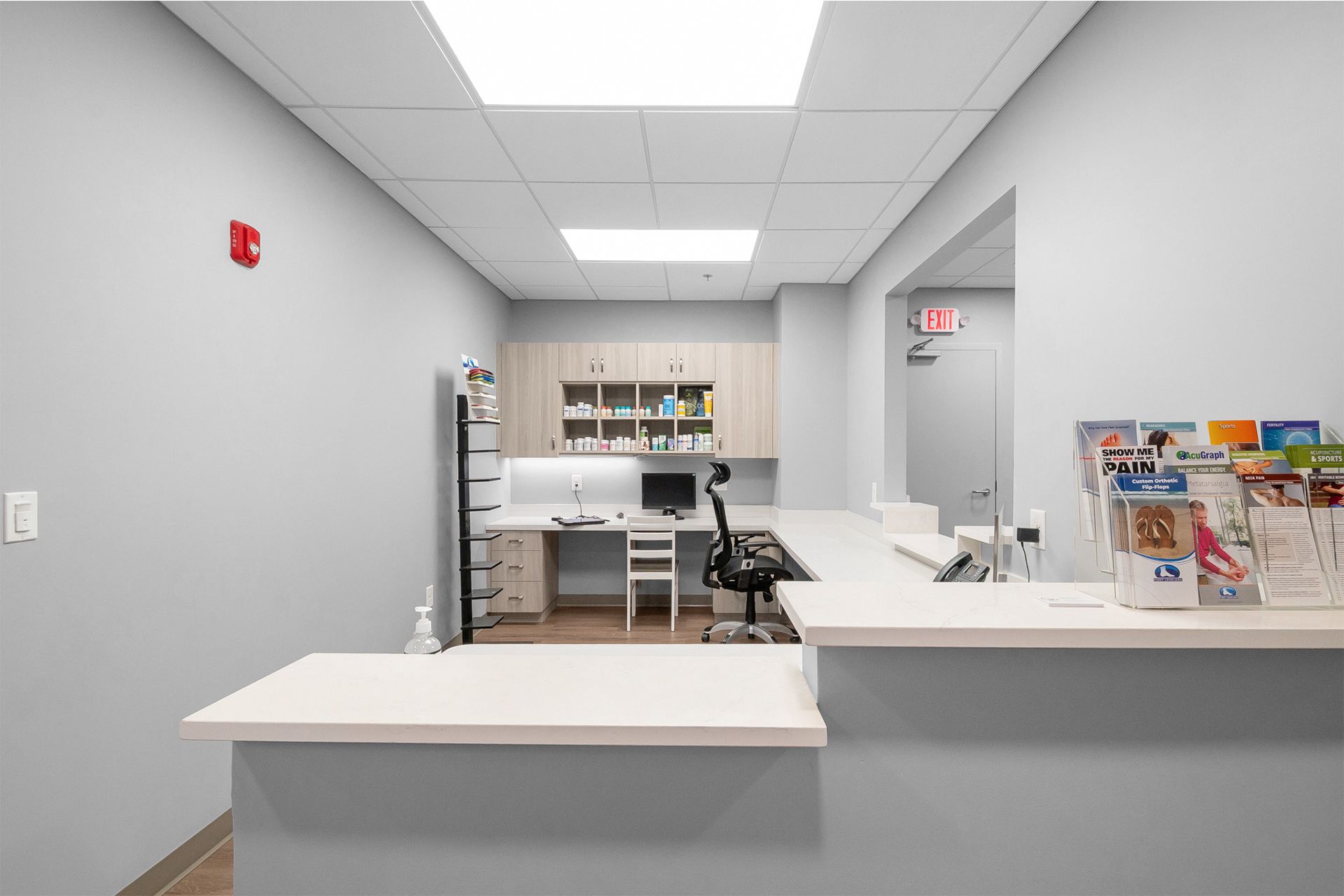 Empty reception area with white counter, gray walls, and fluorescent ceiling lights