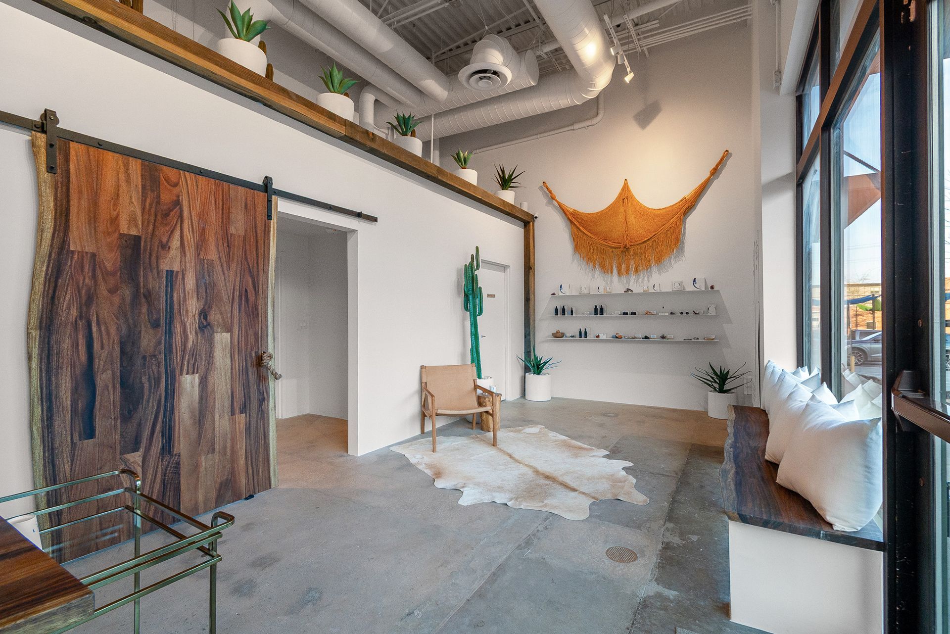 Modern studio interior with large artwork, wooden door panel, chair, and windows with city view.