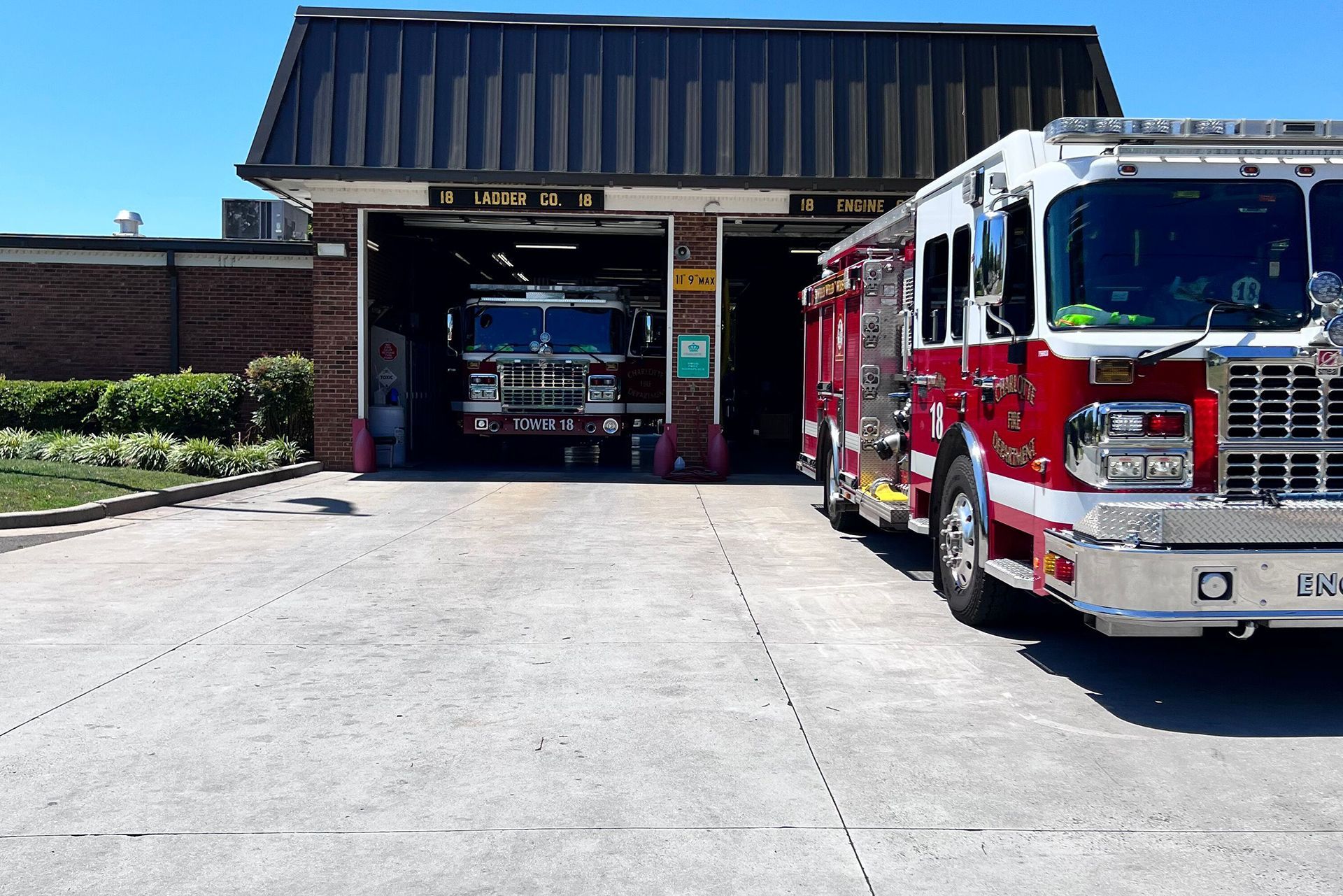 Fire station with two red fire trucks, one inside the bay and one parked outside