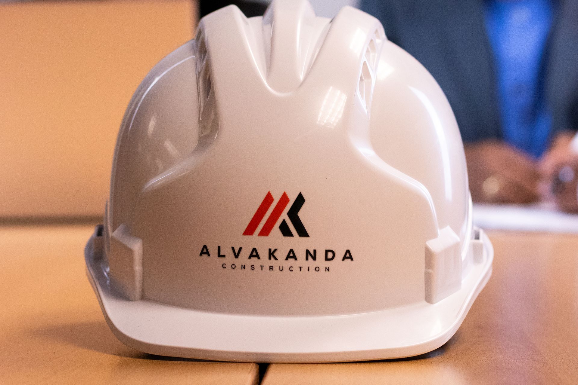 White hard hat with ALVAKANDA logo on a table in a meeting room