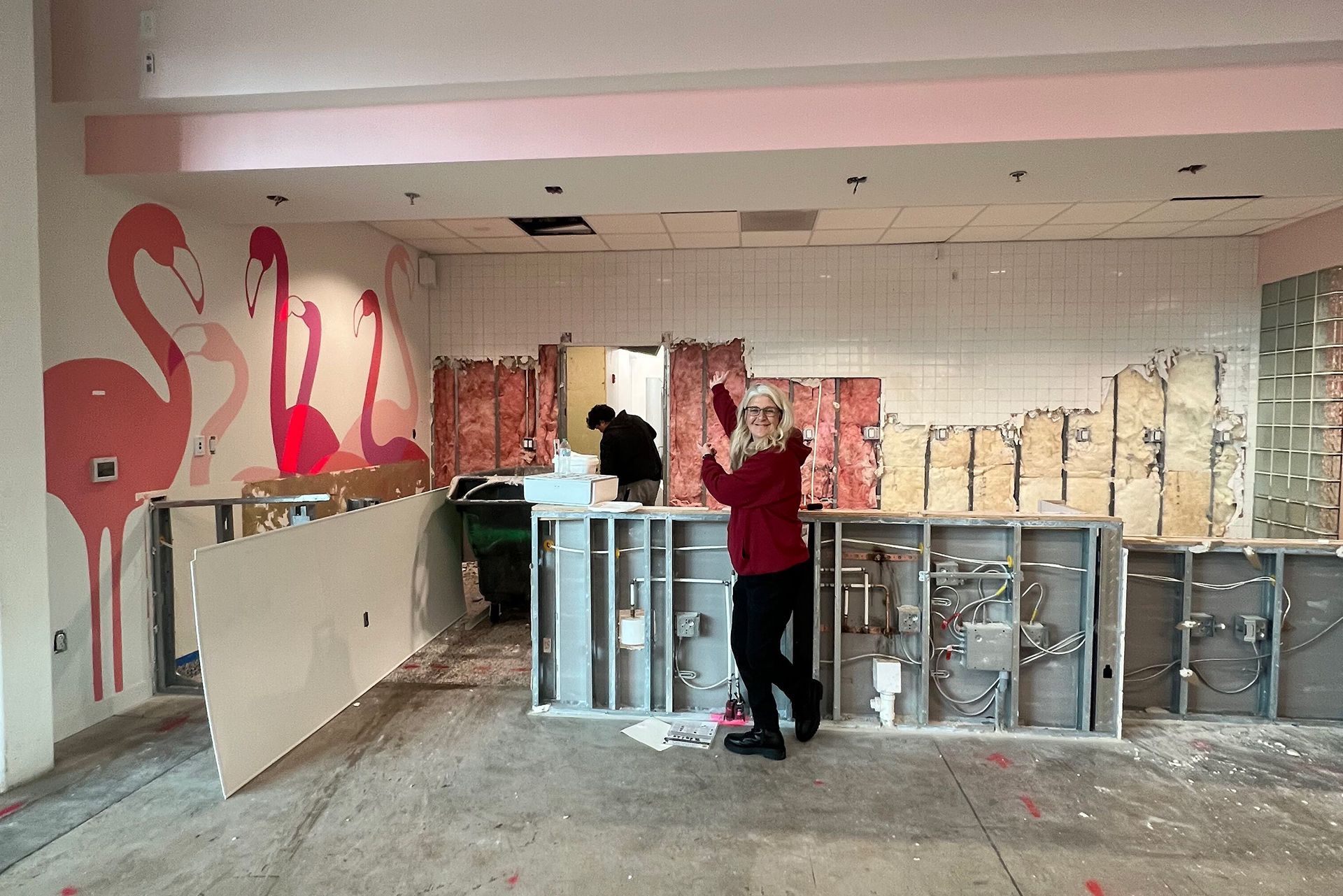 Two people painting graffiti on a wall in a partially renovated interior space