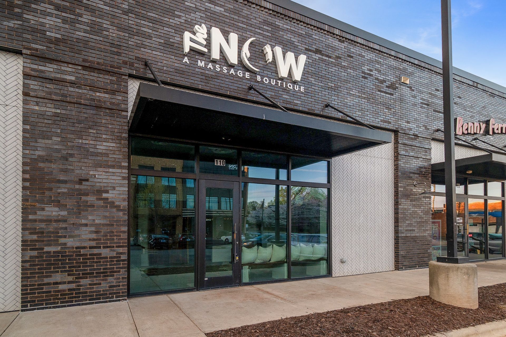 Exterior of NOW apartment building with brick facade and glass entrance doors